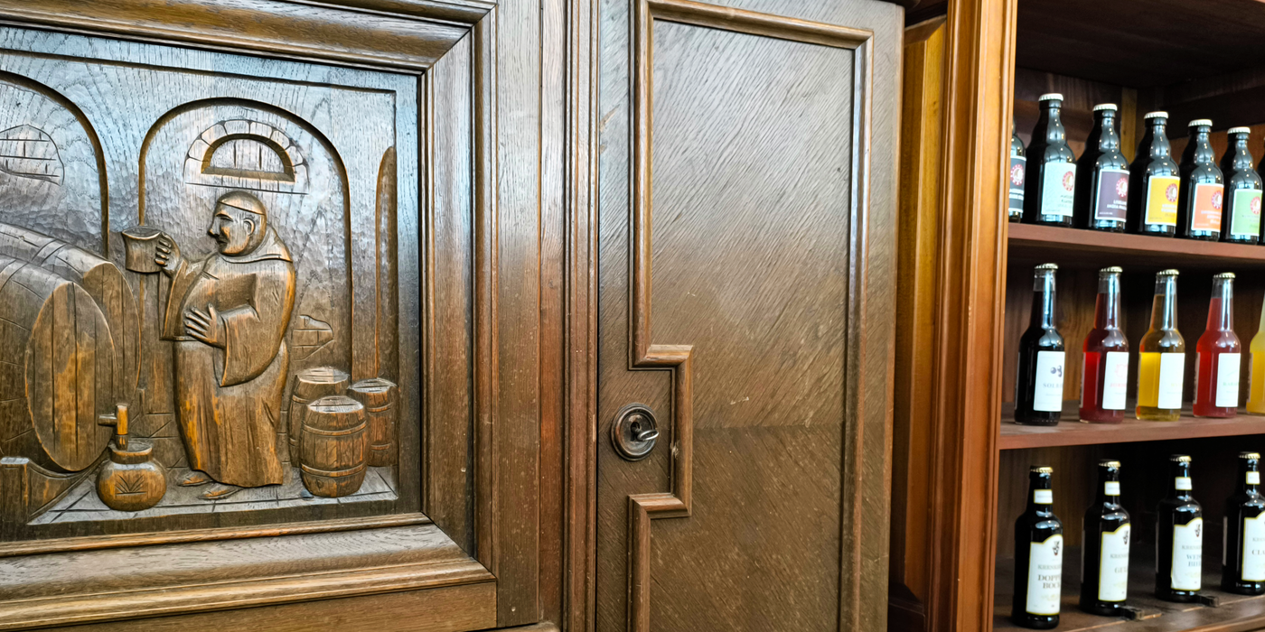 A cozy tavern scene with a beautifully carved wooden cabinet and shelves filled with various beverages.